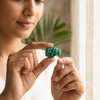 Woman holding a green malachite carving of lion  in her hands with a blurred indoor background