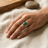 Hand wearing a green malachite gemstone ring on a textured surface