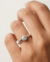 Hand wearing a diamond ring on a neutral background