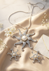 Silver star-shaped jewelry set with pearls on a beige fabric background